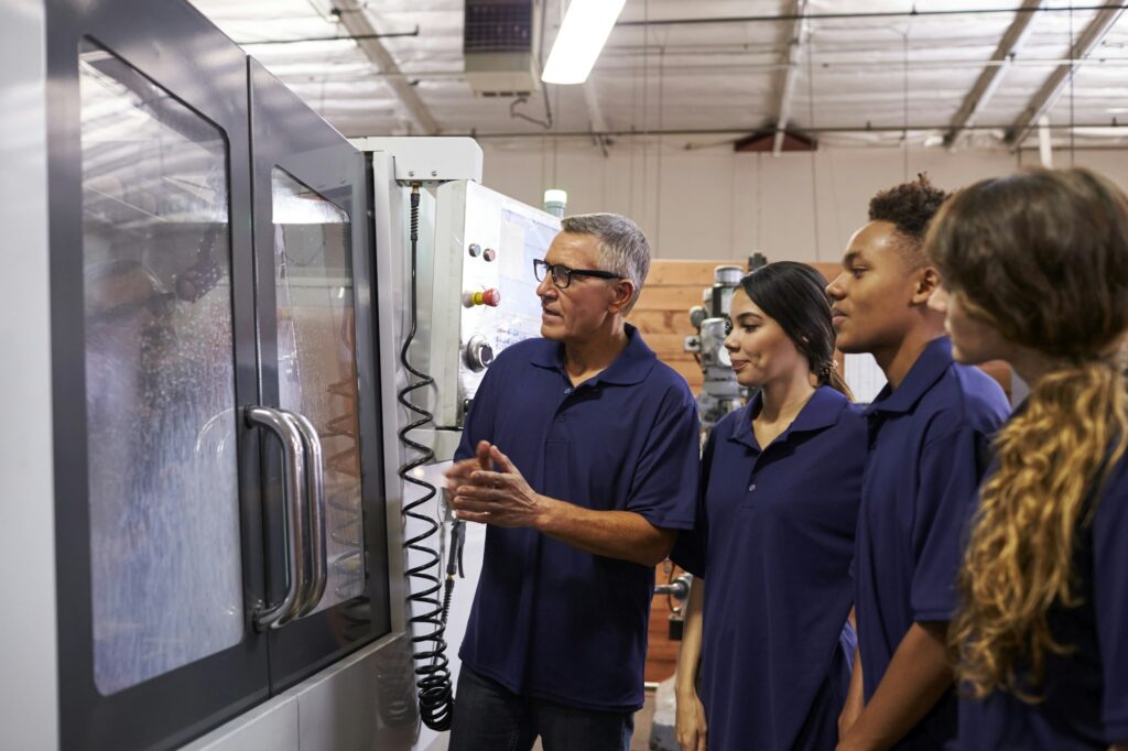 Engineer Training Apprentices On CNC Machine