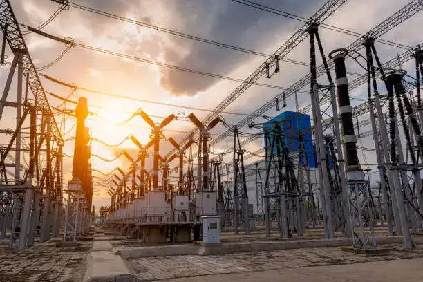 High-voltage electrical substation with transformers, circuit breakers, and power lines at sunset, showcasing advanced power transmission infrastructure.