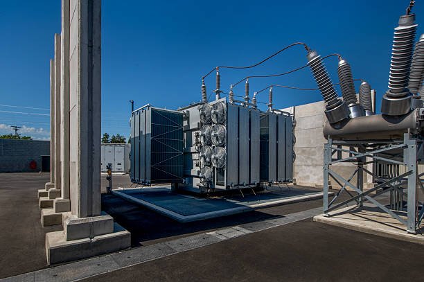High-voltage power transformer installed outdoors on a substation site, featuring cooling radiators and electrical connections, essential for efficient electricity transmission and distribution.