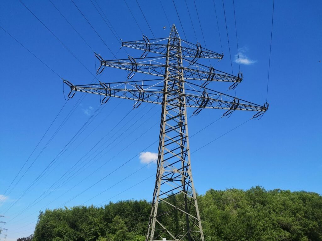 High-voltage transmission tower with multiple power lines against a clear blue sky, showcasing electrical infrastructure for efficient power distribution.