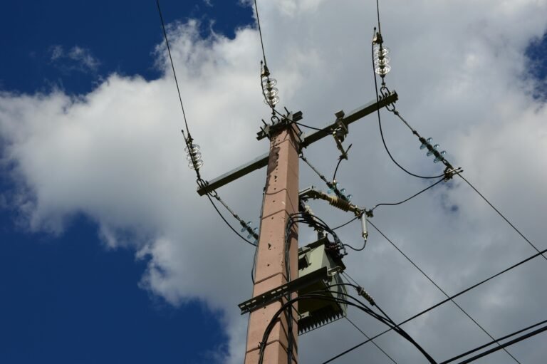 High-voltage power line pole with electrical insulators and wires against a partly cloudy sky, showcasing electrical infrastructure and transmission technology.