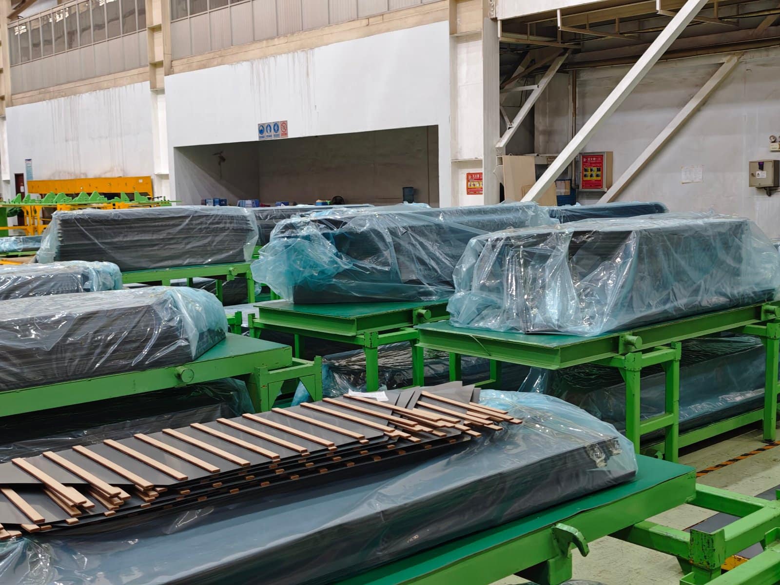 High-voltage power transformers stored on green racks in an industrial warehouse, ready for installation or shipment.