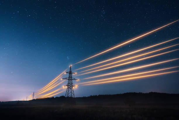 High-voltage power lines and transmission towers at night with starry sky background, illustrating electrical energy transmission.